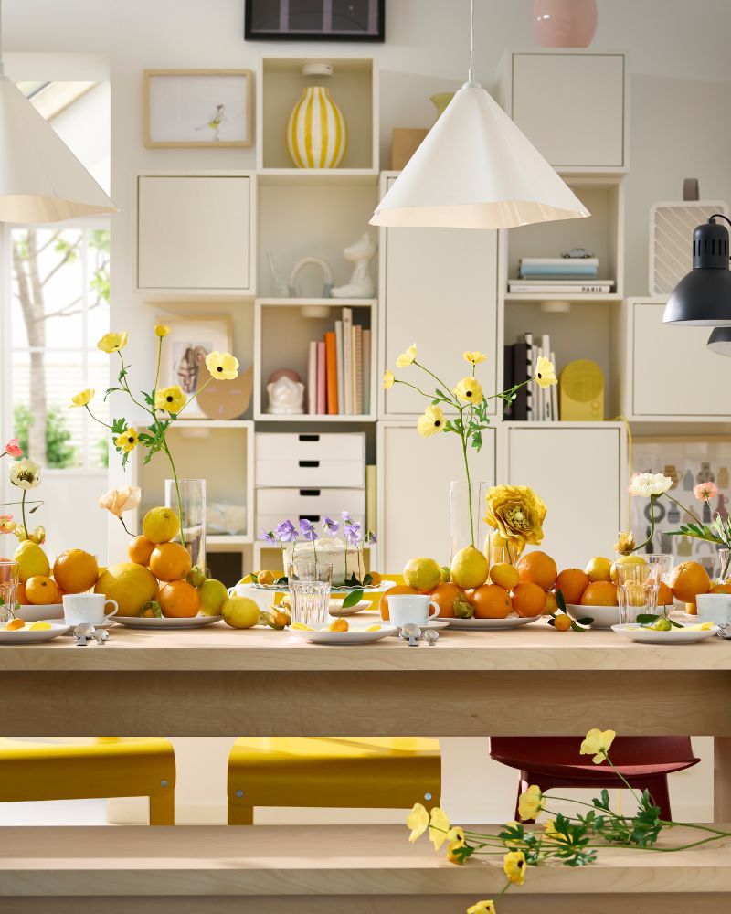 A BERGSHYTTAN table has a table setting with white plates and POKAL glasses and decorative oranges and lemons on plates.