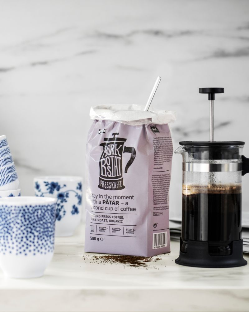 Bright coffee counter scene with PÅTÅR ground press coffee, UPPHETTA coffee maker and ENTUSIASM cup.