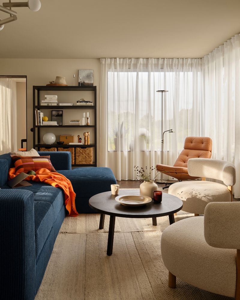  living room with a dark-blue JÄTTEBO four-seat sofa with chaise longue next to STOCKHOLM 2025 armchairs and coffee table.