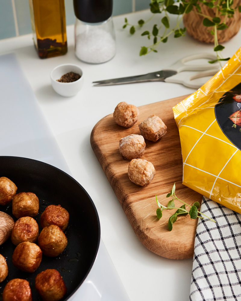 IKEA HUVUDROLL chicken meatballs on a skillet and a wooden board.
