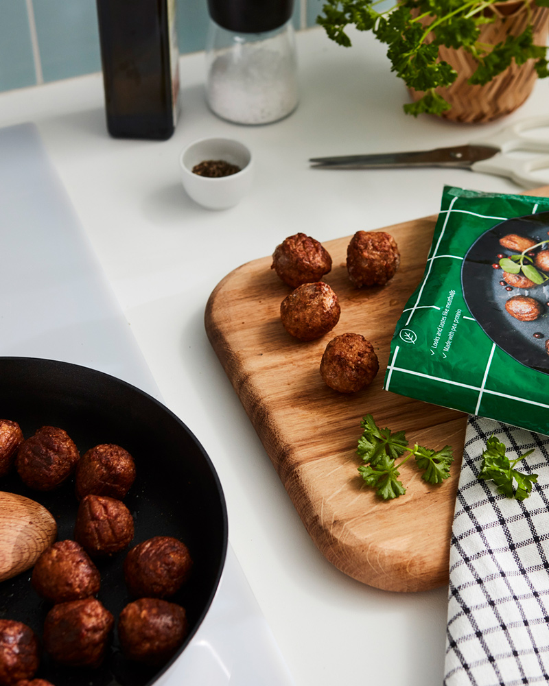 IKEA plant-based protein meatballs on a skillet and a wooden board.