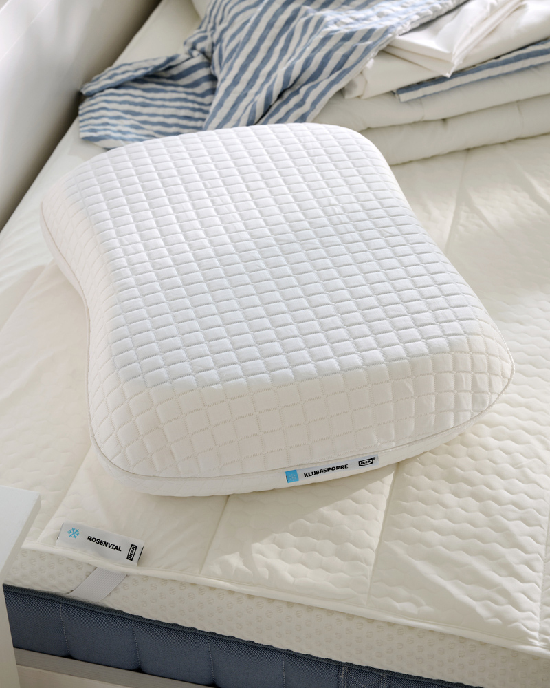 Close-up of KLUBBSPORRE ergonomic pillow on top of ROSENVIAL mattress protector, both in a cooling material.