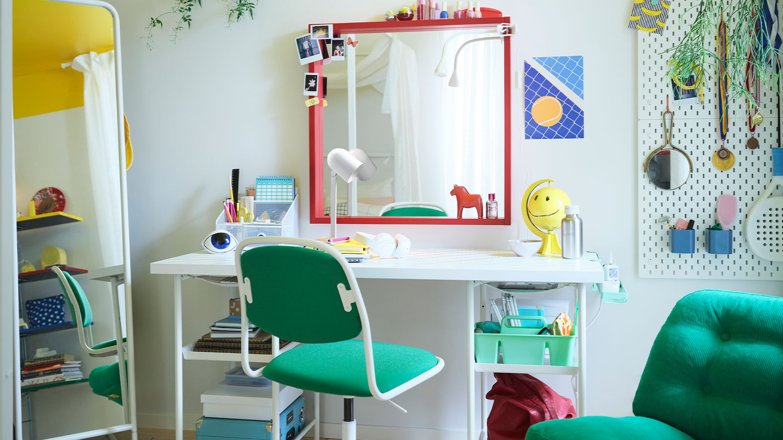A teen bedroom with a large white bed, a desk with a big red mirror above it, a green desk chair and armchair, and more.