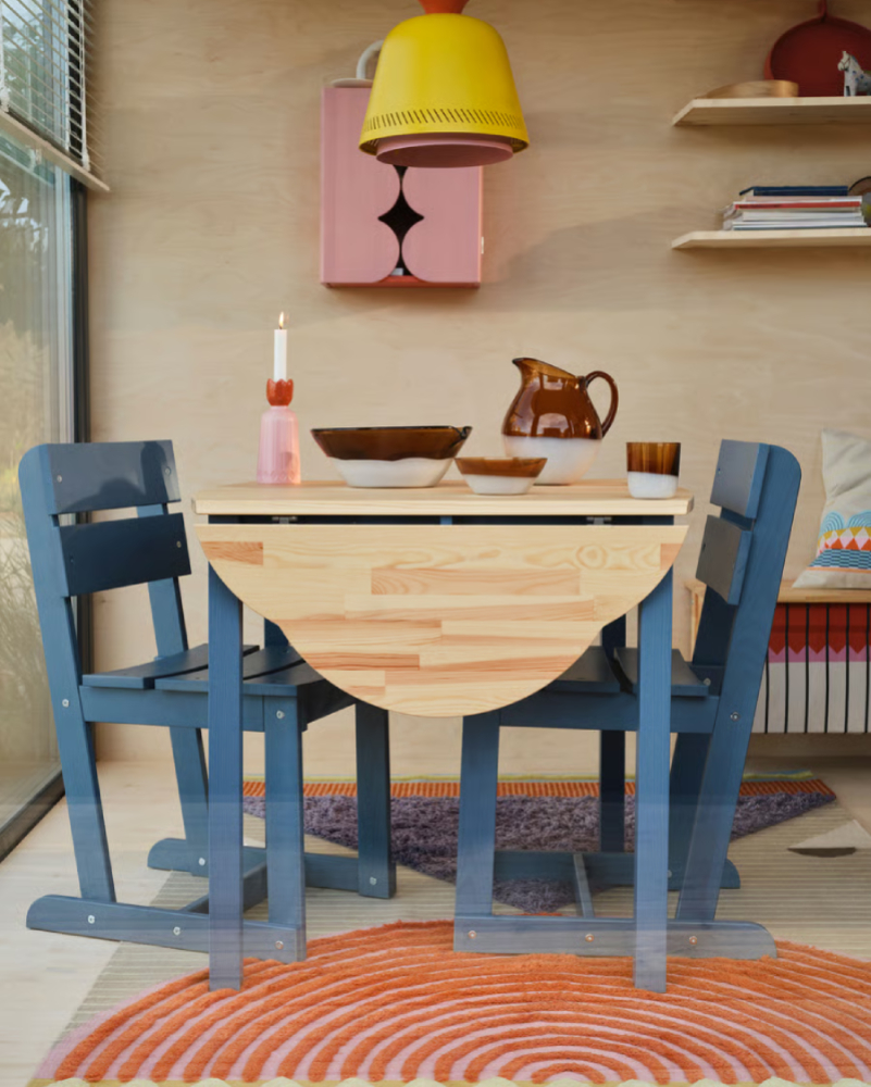 Wooden side table with two traditional-style chairs in an antique industrial setting.