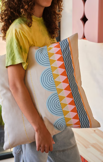 Person with a large cushion under their arm, in autumnal colors, with flat geometric shapes and figures.