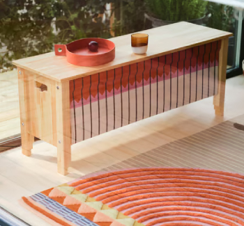Handcrafted wooden bench with autumn-colored front, deep red tray, rustic glass, and matching handmade rug in warm tones.