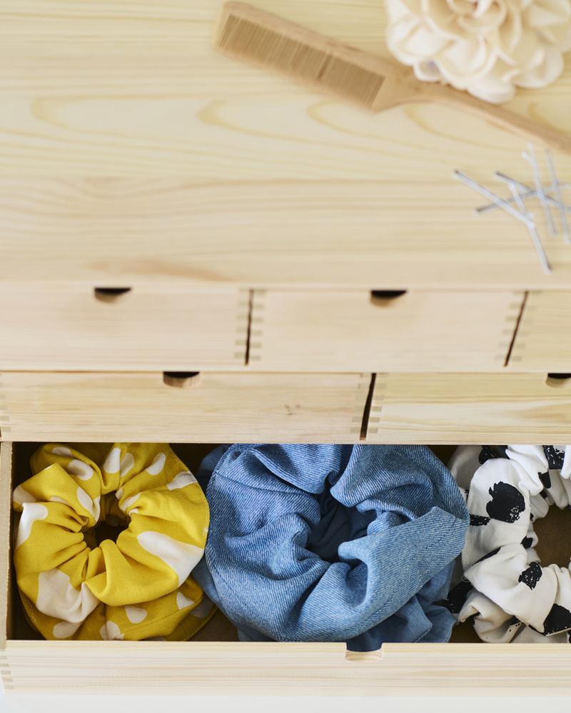 A pine MOPPE minni chest with the bottom drawers open showing three rows of different coloured hair scrunchies.