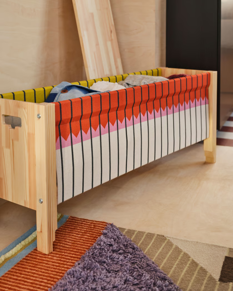 Handcrafted wooden bench with an open front in autumnal colors, revealing the colorful fabrics inside.