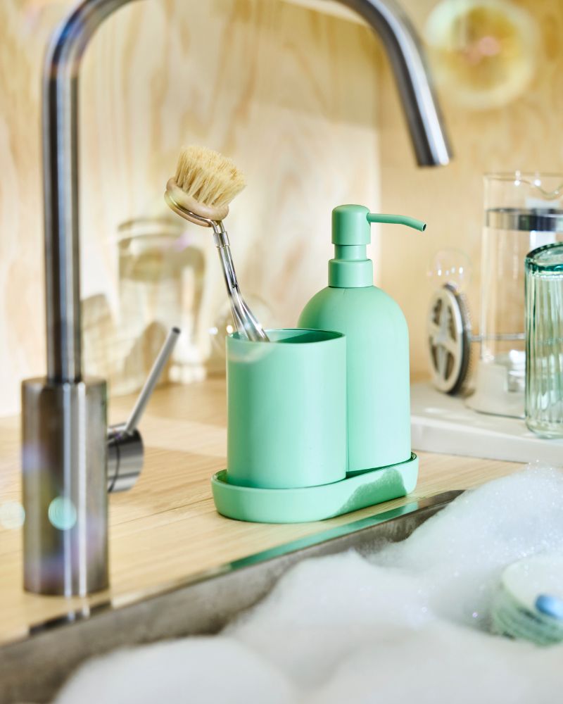 Green stoneware GANSJÖN soap dispenser,  vessel and soap dish by the sink in a  Scandinavian modern kitchen.