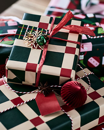 Christmas presents are festively wrapped in VINTERFINT gift wrappers with a bold green and red checkered pattern.