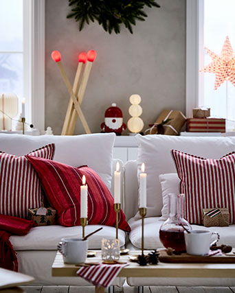 Three red-striped VINTERFINT cushion covers are on a sofa, in a living room that is decorated for Christmas.