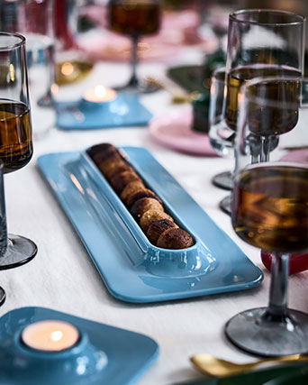 A row of meatballs is on a blue VINTERFINT serving plate, on a festively decorated table.