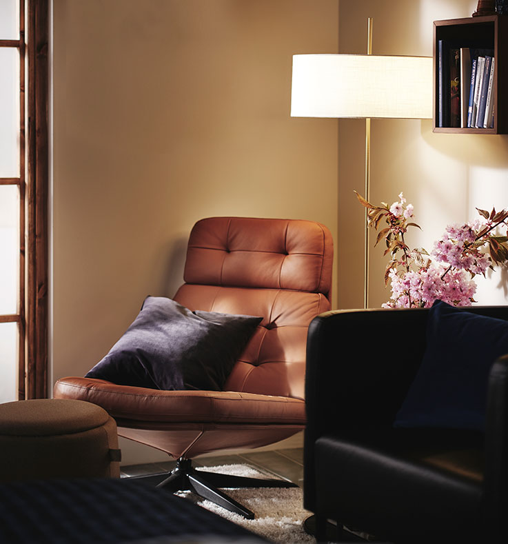 Relaxing corner in a bedroom with HAVBERG and EKERÖ armchairs, a side table, flowers, a floor lamp and a wall clock.