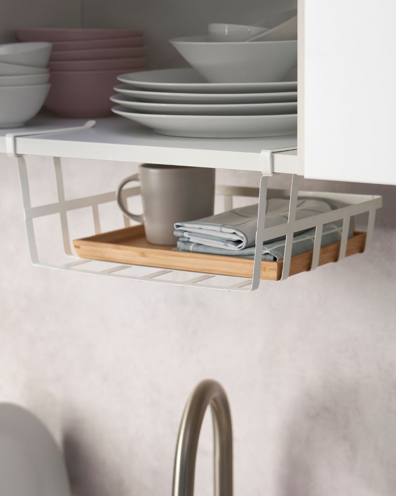 A KNOXHULT wall cabinet has an open door and a hanging basket with PÅLYCKE clips.