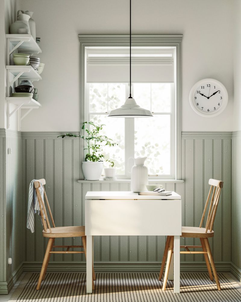 A HAUGA drop-leaf table in white and birch veneer and two HÖGVED chairs in birch veneer are placed next to a window.