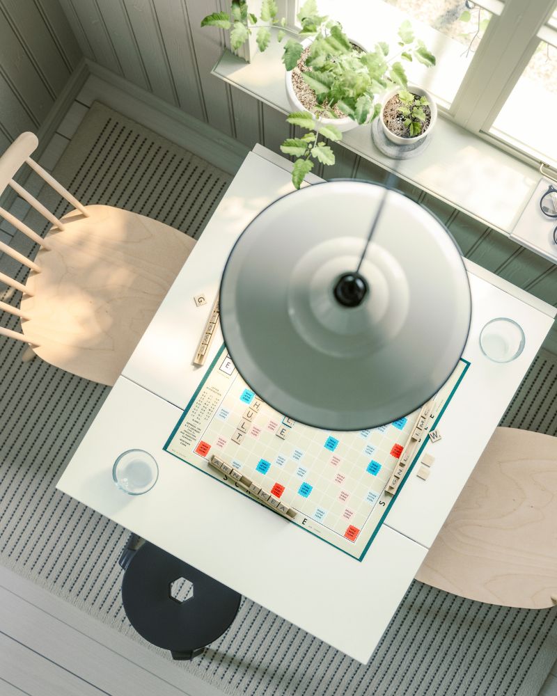 An eagle-eye’s view of a HAUGA drop-leaf table in white and birch veneer, with HÖGVED chairs, placed next to a window.