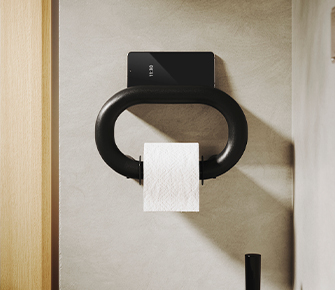 Black toilet paper holder mounted on wall with white toilet paper roll