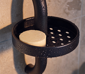 Black metal cup holder with perforated design holds a wooden disc. Practical wall-mounted storage for organizing small items