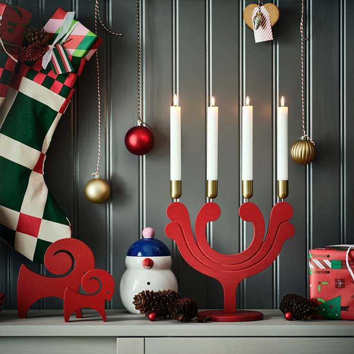 Holiday decorations on kitchen shelf with heart-shaped gingerbread cookies, red wooden reindeer ornaments, ceramic snowman jar, glass containers with festive ribbons and evergreen sprigs