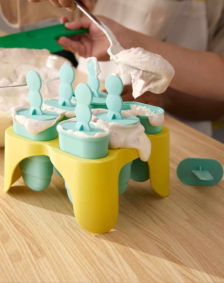 A close-up of yellow and green UPPFYLLD ice lolly makers being filled with yoghurt to become popsicles.