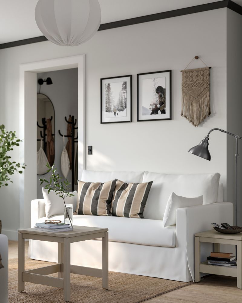 A HYLTARP 2-seat sofa, with two extra cushions on it, stands against a wall near a set of 2 HAVSTA nest tables.