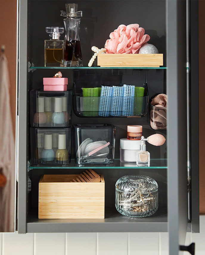 Close-up of a dark grey HAVBÄCK wall cabinet with  open door, displaying organised toiletries and  bathroom accessories.
