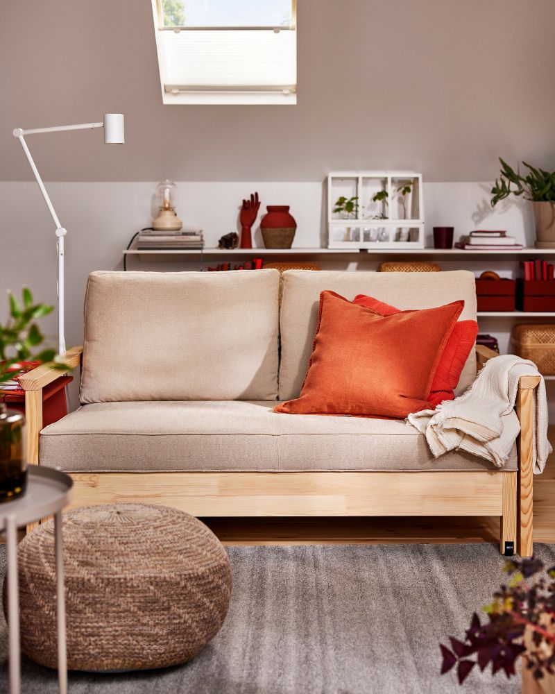 A TORNSBORG sofa-bed with a throw and extra cushions on it, including one with a red-brown DYTÅG cushion cover.