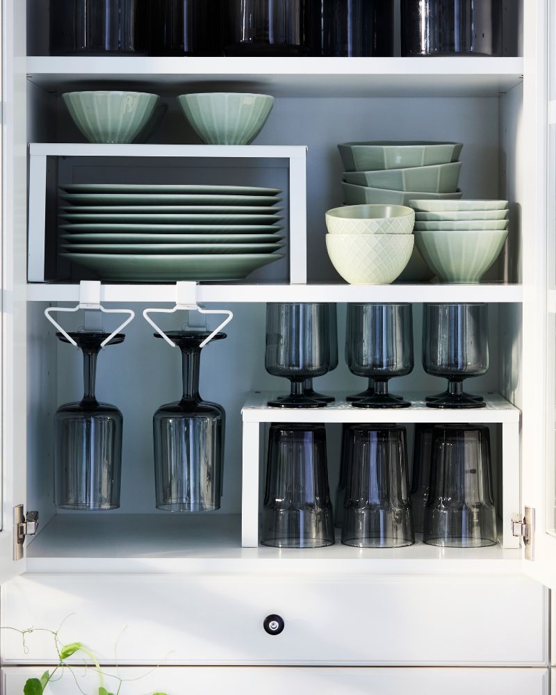 A neatly arranged kitchen wall cabinet fitted with PÅLYCKE and VARIERA organisers containing tableware and drinking glasses.
