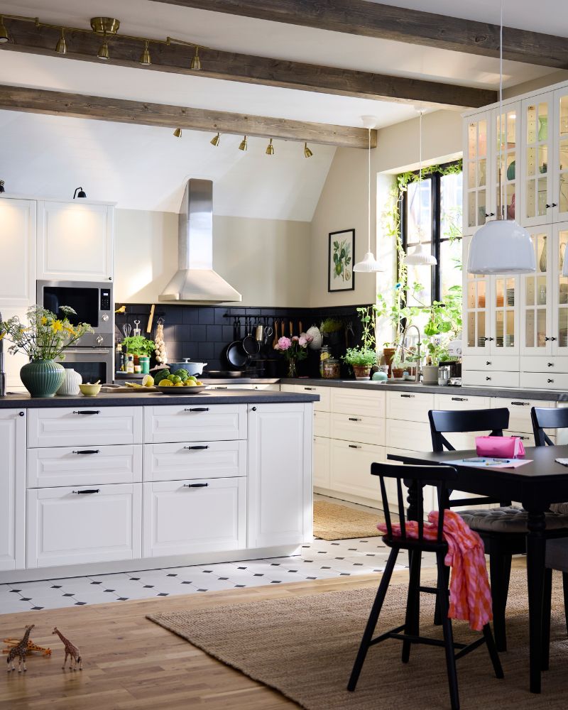 A large, traditional style kitchen with white BODBYN fronts including a kitchen island and a dining suite in dark wood.