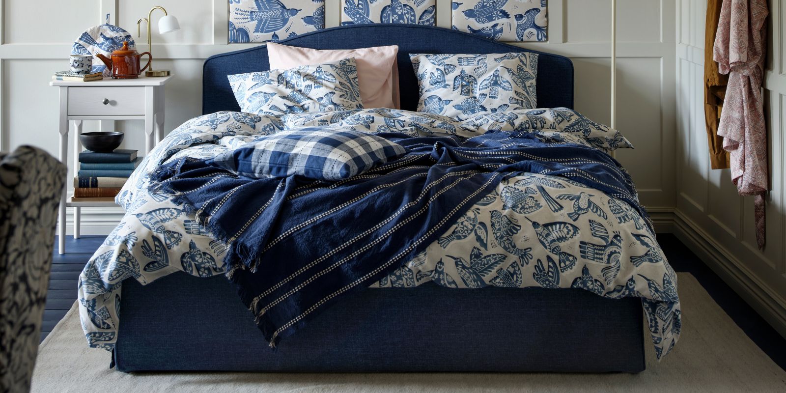 A dark blue RAMNEFJÄLL upholstered bed frame together with a BITTERSÖTA duvet cover and pillowcase set and pre-cut fabric
