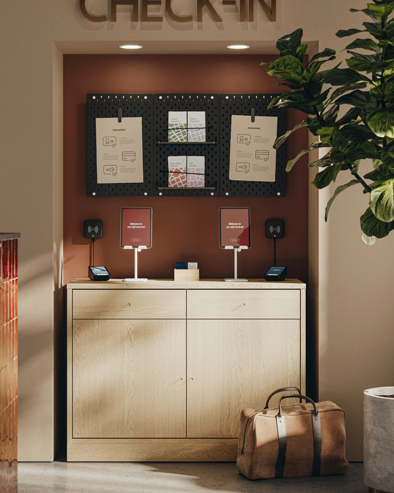 Reception self-check-in station made with TONSTAD oak veneer sideboard holding check-in tablets, brochures, and information.