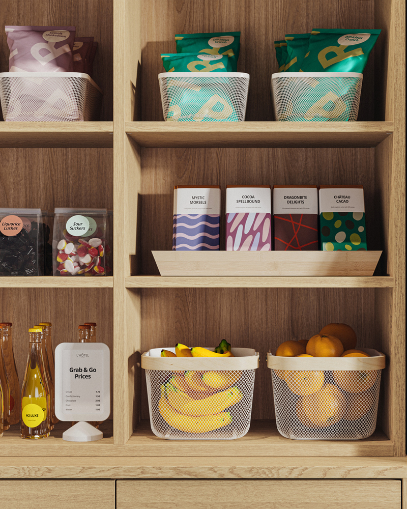 Close-up of a TONSTAD shelving with two white RISATORP baskets that holds fruit alongside more neatly arranged food items.