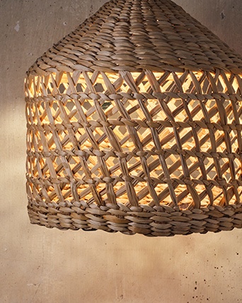 The MÄVINN pendant lampshade hangs in front of a grey concrete wall. The light is lit, which enhances the cut-out pattern.