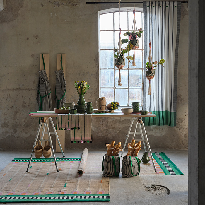 Parts of the MÄVINN collection are displayed on a table and hanging in front of a window in a room with an industrial look.