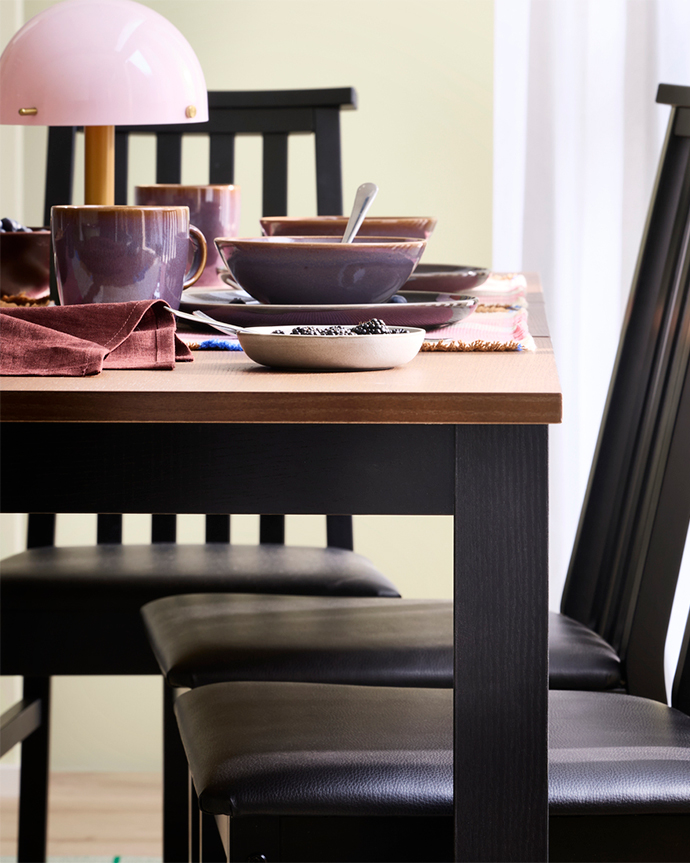 A brunch table setting for two, with coffee, juice, fresh fruit and croissants, is placed on an ÅLHULT extendable table.