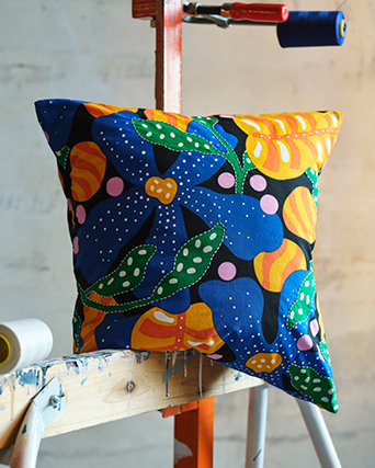 Hands weaving a circular base from natural fiber with circular patterns in white, black, and cream.