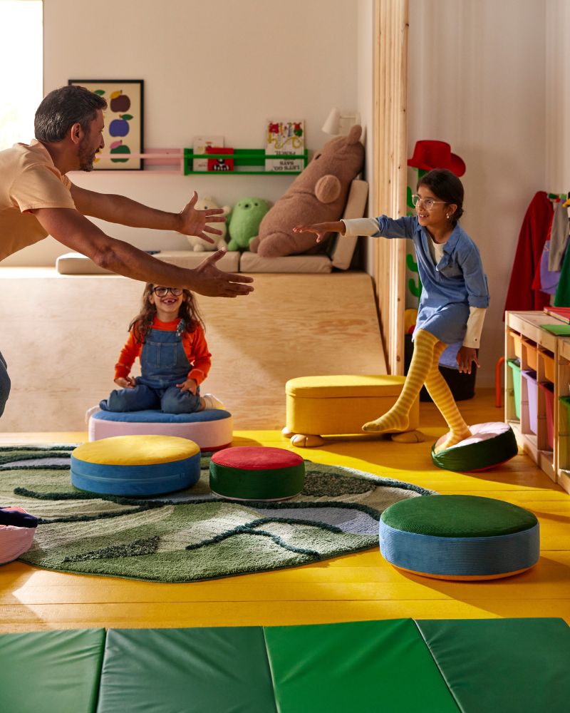 In a parent and two children play a game of Floor is Lava while using GREJSIMOJS floor cushions and a GRESIMOJS rug.