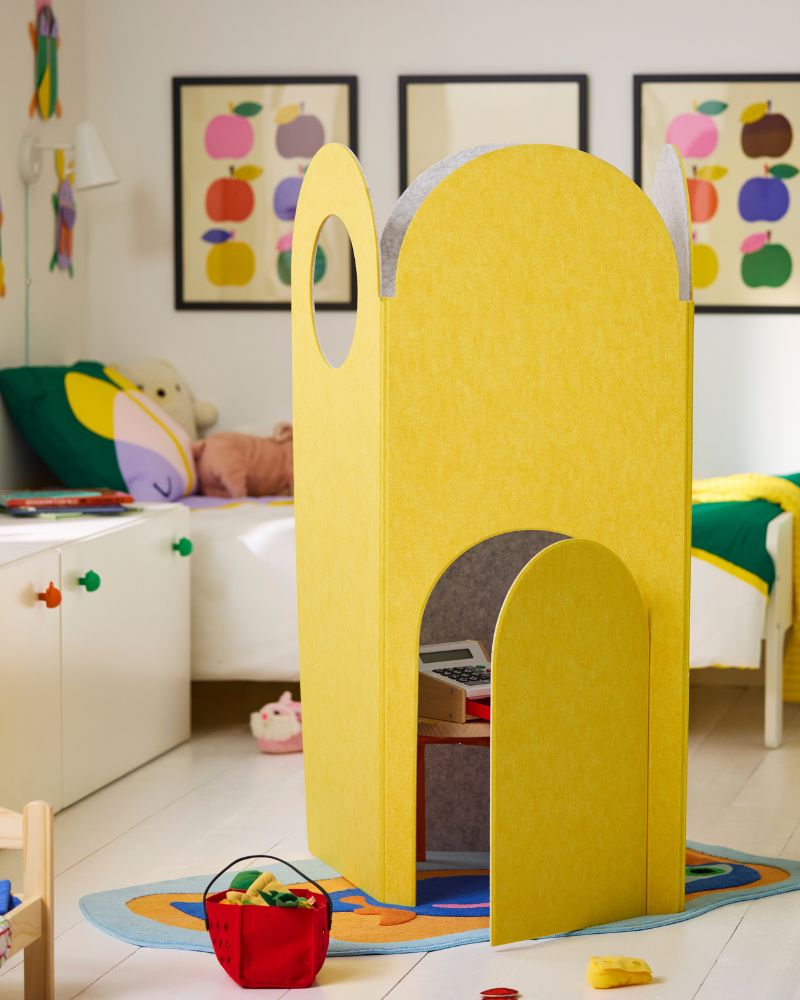 In a child's bedroom, a GREJSIMOJS room divider is set up as a tower with a GREJSIMOJS stool and a toy cash register inside.