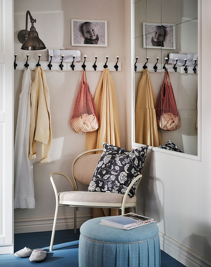 A grey-beige ISMANTORP armchair in the corner of a room with a blue ÅTERLÖGA pouffe with storage in front with a book on top.
