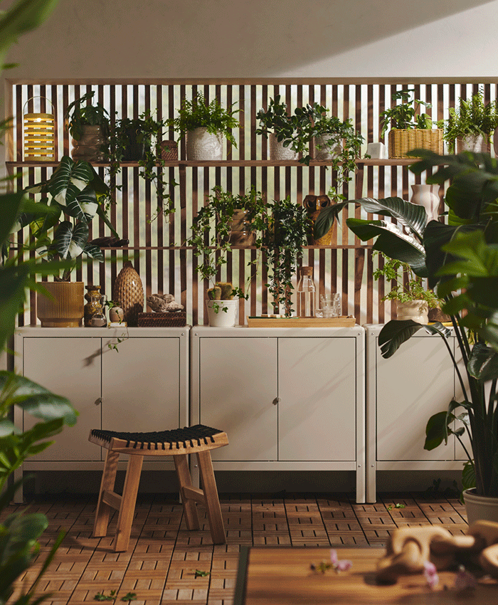 Outdoor storage solution with beige metal cabinets and wooden shelving filled with potted plants against a slatted privacy screen.