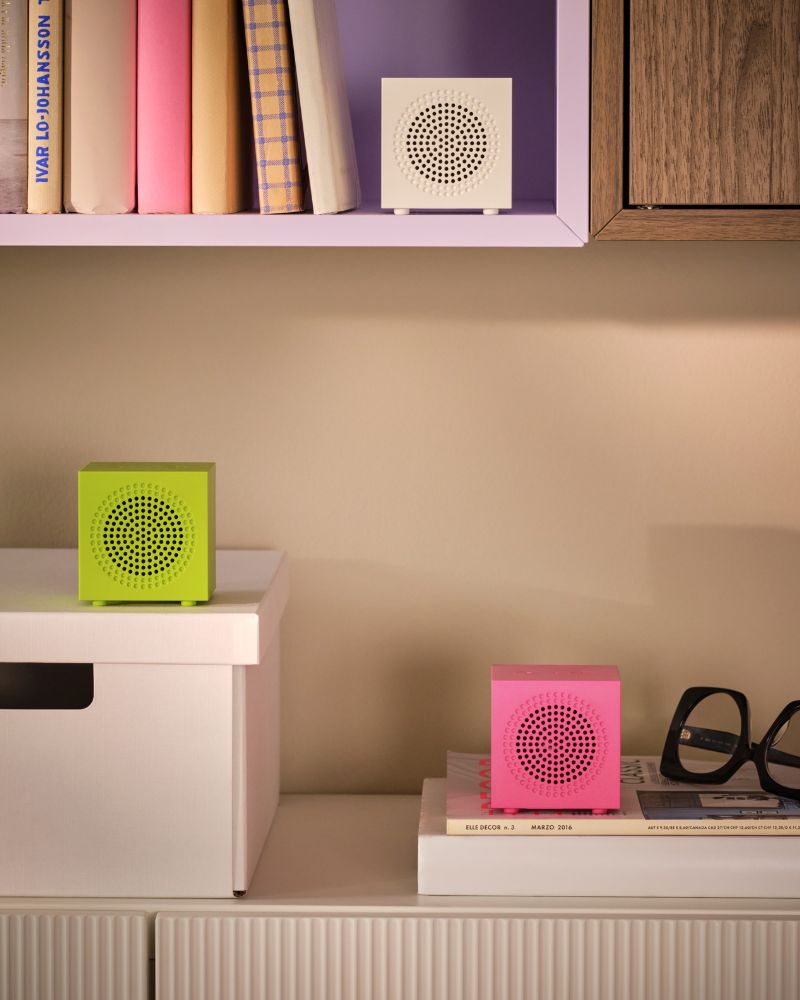 An arrangement of wall cabinets holds books, a box and three KALLSUP portable Bluetooth speakers in different colours.