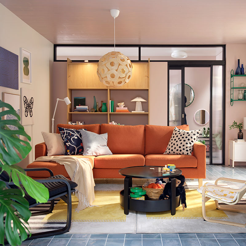 A light living room with a red-brown SALTSJÖBADEN three seat sofa flanked by armchairs, coffee table and toys.