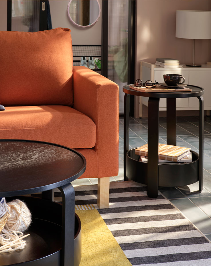 A light living room with a black BORGEBY side table and coffee table, both placed near a red-brown SALTSJÖBADEN sofa.