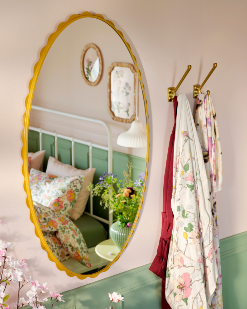bedroom wYellow DAGGKAPRIFOL wall mirror with round details on the frame that reflect the bed in the room.ith mirror