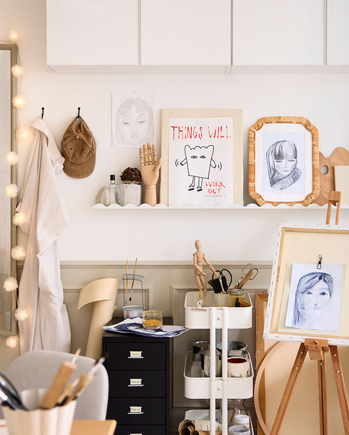 A craft area in a bedroom featuring a white DAGGKAPRIFOL picture ledge displaying artwork and decorative items on the wall.
