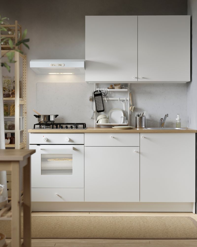 Modern minimalist kitchen with SEKTION wall cabinets, gas cooktop, SUNNERSTA rail, and IVAR shelving with KORKEN jars.
