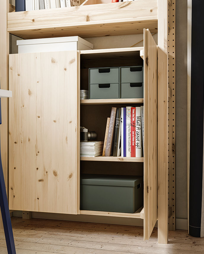 A bright space with an IVAR shelving unit, one pine cabinet door open to reveal books and storage boxes neatly arranged.