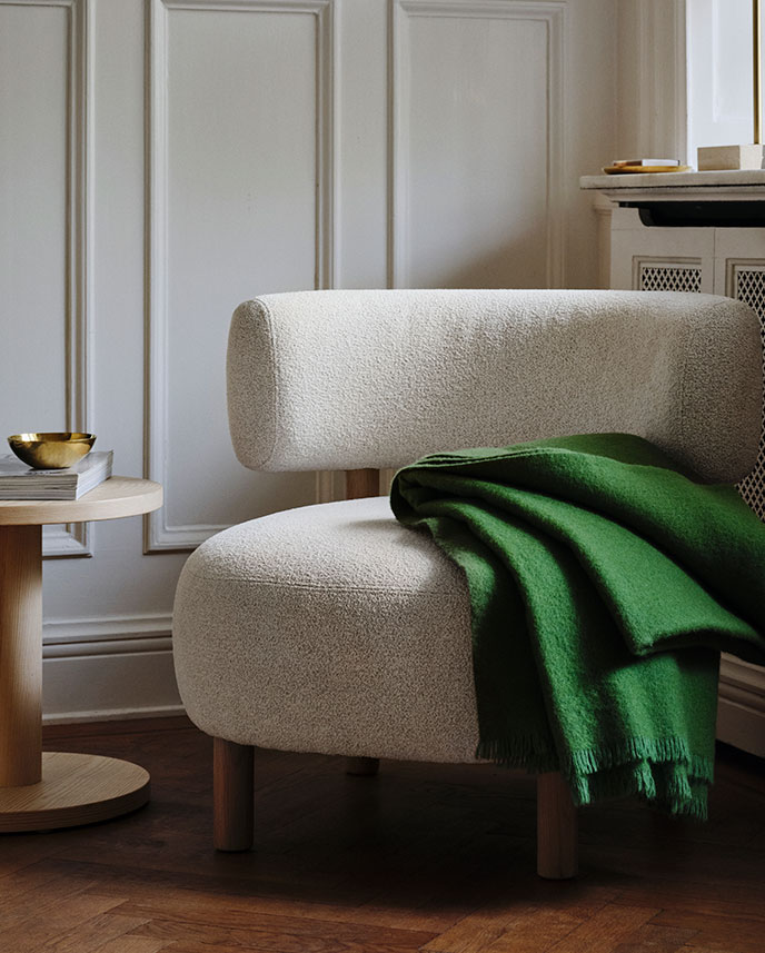 A bright living room with a FRYKSÅS cabinet made of rattan, displaying decorative items and surrounded by plants.