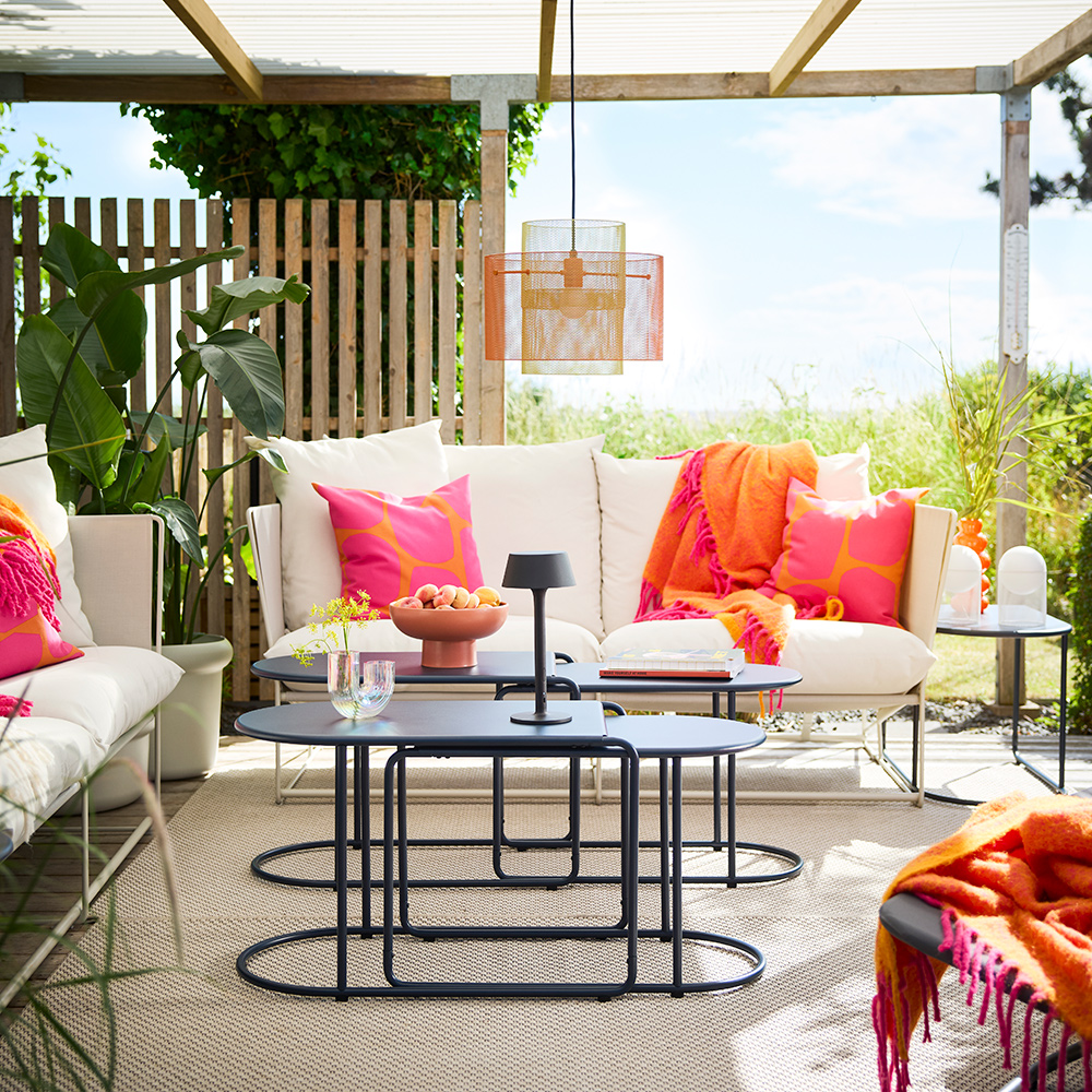 An oudoor lounge area under a roof top terrace featuring black-blue GRYTSHOLM nest of tables with fruits and decorations.