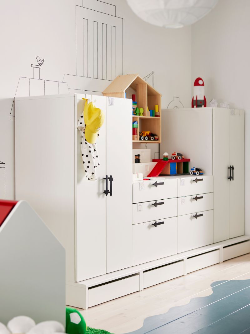 White SMÅSTAD/PLATSA storage units with JÄRNSPARV black handles against a wall with a FLISAT doll’s house/shelf on it.